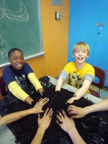 kids workshop: two boys mixing soil, many hands